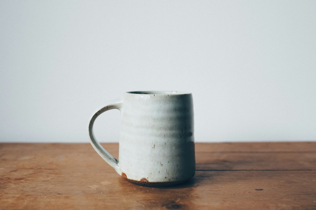 A wheel-thrown stoneware mug with a soft ash glaze