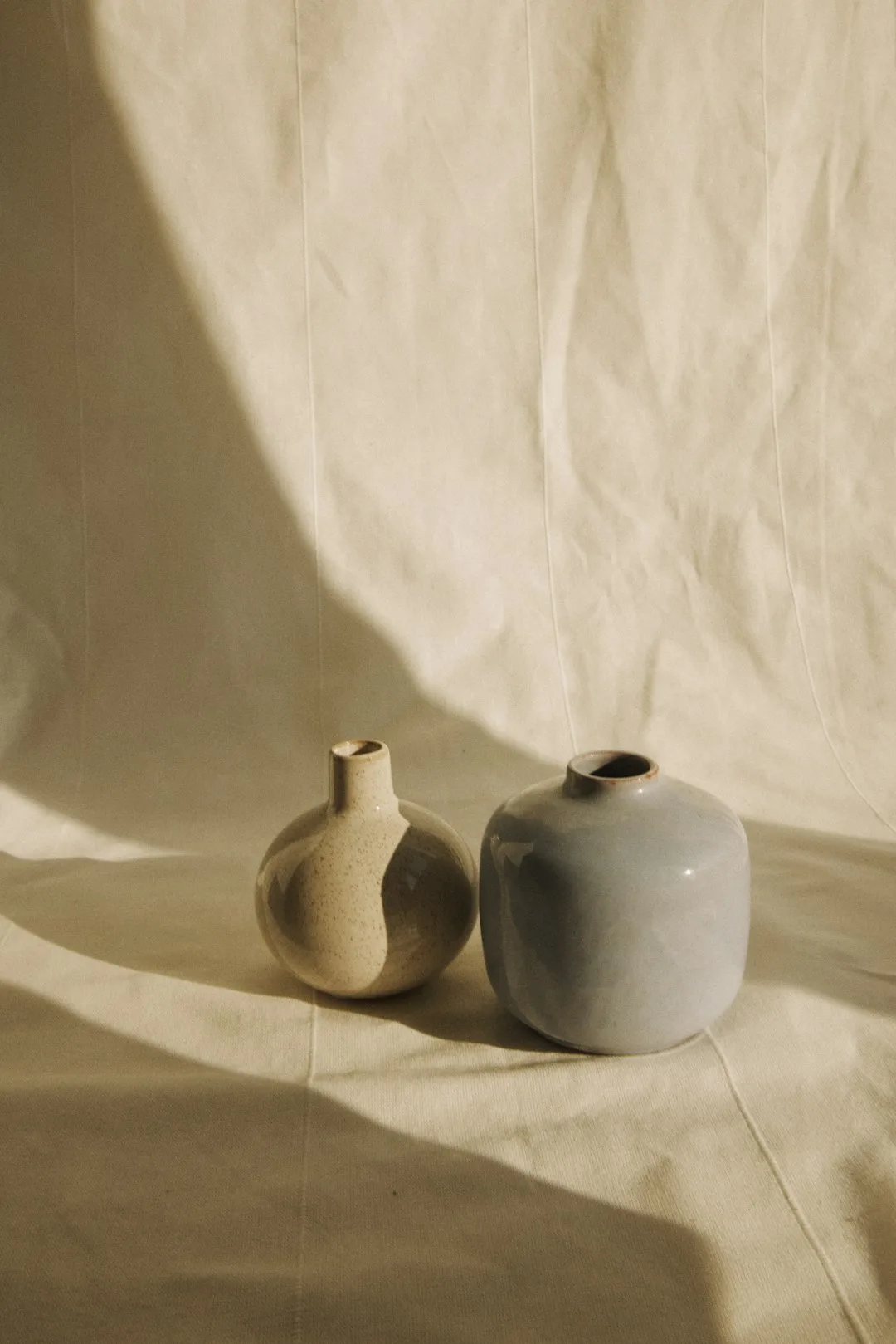A tall wheel-thrown bud vase with an iron-speckled glaze