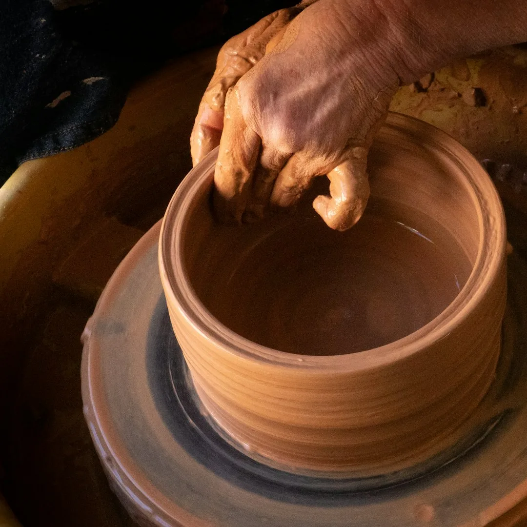 A pair of hands centering clay on a pottery wheel